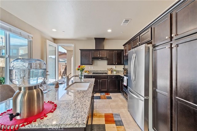 kitchen featuring sink, dark brown cabinetry, stainless steel appliances, light tile patterned floors, and light stone counters