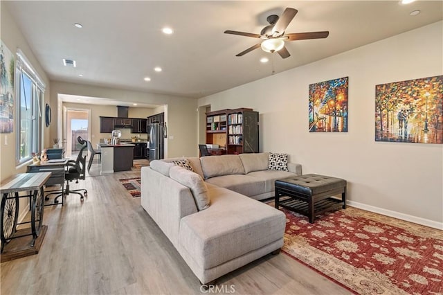 living room featuring ceiling fan and light hardwood / wood-style flooring