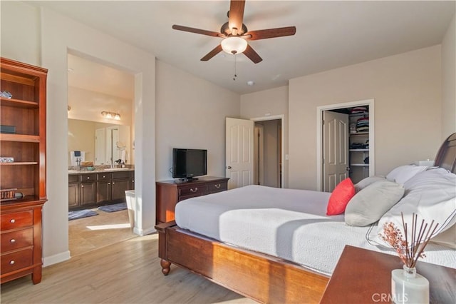 bedroom with light hardwood / wood-style floors, ceiling fan, ensuite bath, a walk in closet, and sink