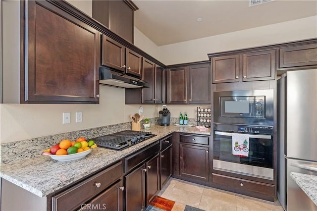 kitchen with light tile patterned floors, light stone countertops, stainless steel appliances, and dark brown cabinetry