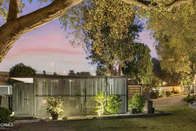 gate at dusk featuring a lawn