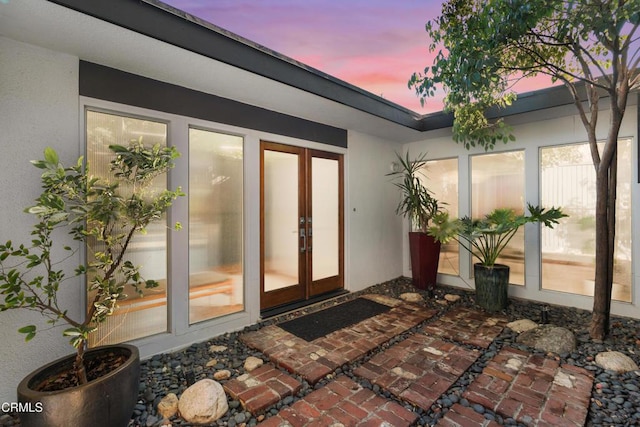 exterior entry at dusk featuring french doors and a patio area