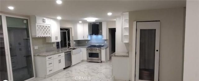 kitchen featuring light stone counters, wall chimney range hood, white cabinets, stainless steel appliances, and backsplash