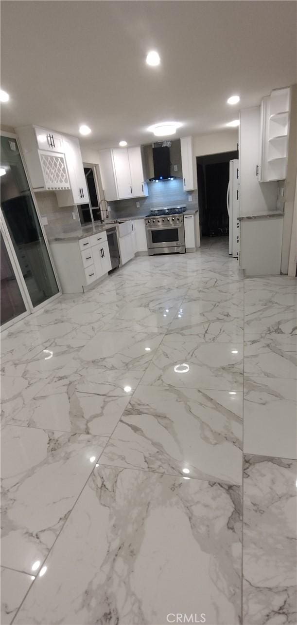 kitchen featuring white refrigerator, dishwasher, white cabinets, high end stove, and wall chimney range hood