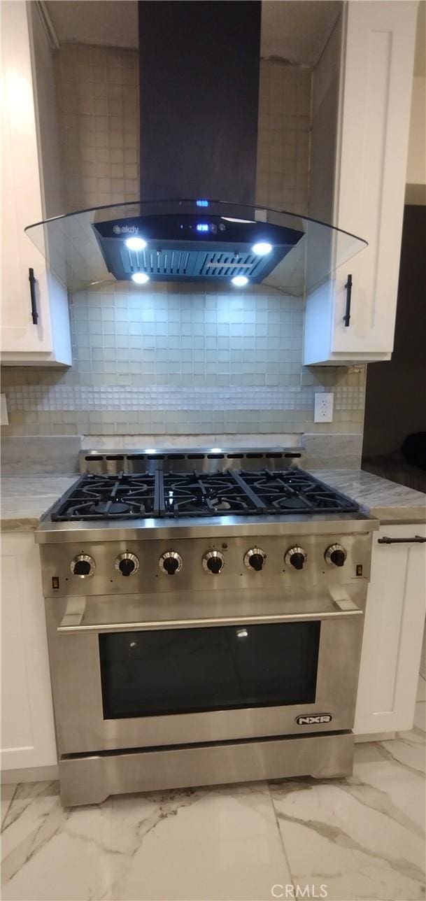 kitchen with backsplash, high end range, wall chimney exhaust hood, and white cabinets