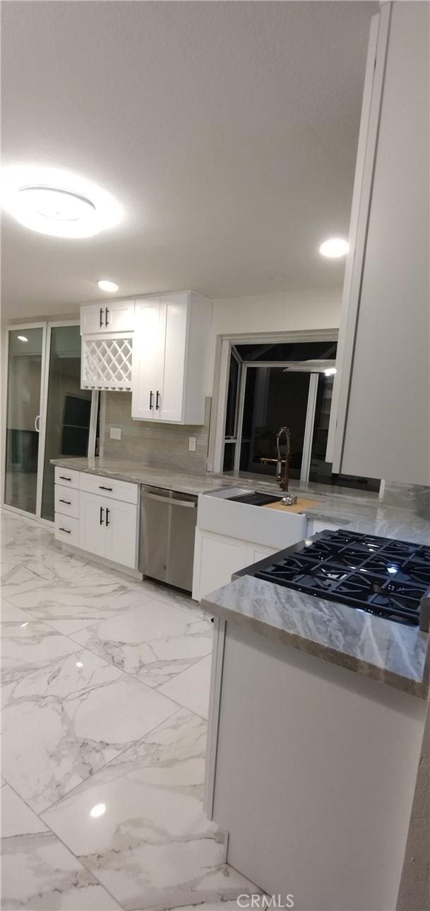 kitchen featuring sink, backsplash, stainless steel dishwasher, and white cabinets