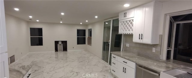 kitchen with white cabinetry, backsplash, light stone counters, and stainless steel dishwasher