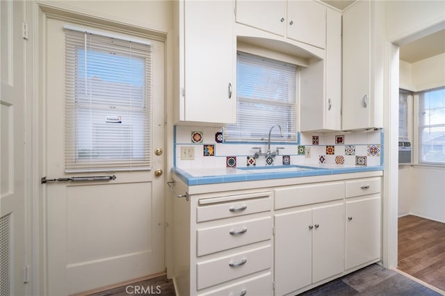 kitchen featuring backsplash, dark hardwood / wood-style floors, sink, and white cabinetry