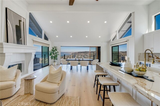 living room with high vaulted ceiling, a high end fireplace, light hardwood / wood-style floors, and beamed ceiling