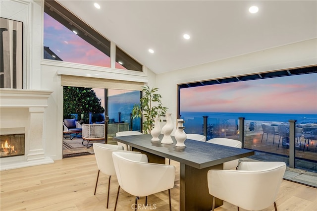 dining area featuring high vaulted ceiling, a high end fireplace, and light wood-type flooring