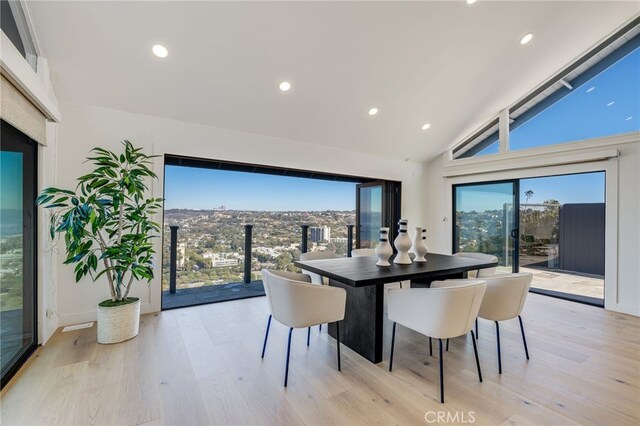 dining area with high vaulted ceiling and light hardwood / wood-style floors