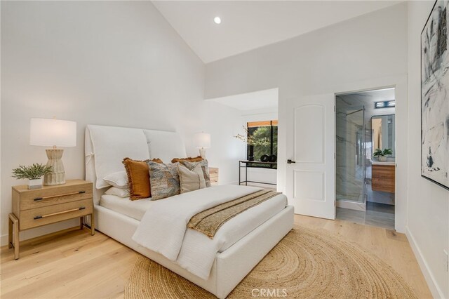 bedroom featuring hardwood / wood-style flooring, high vaulted ceiling, and ensuite bath