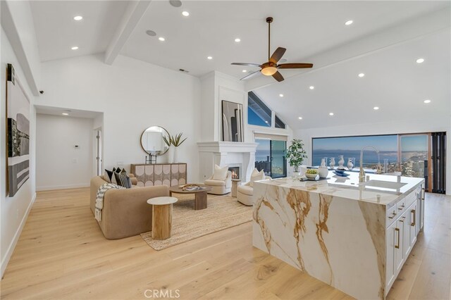 living room featuring high vaulted ceiling, beam ceiling, light hardwood / wood-style floors, and sink