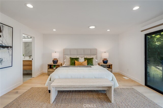 bedroom with ensuite bath, light hardwood / wood-style floors, and access to outside