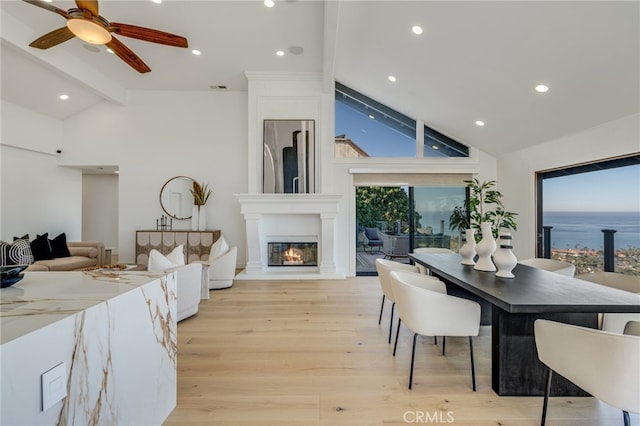 dining area with beamed ceiling, a fireplace, high vaulted ceiling, and light hardwood / wood-style flooring