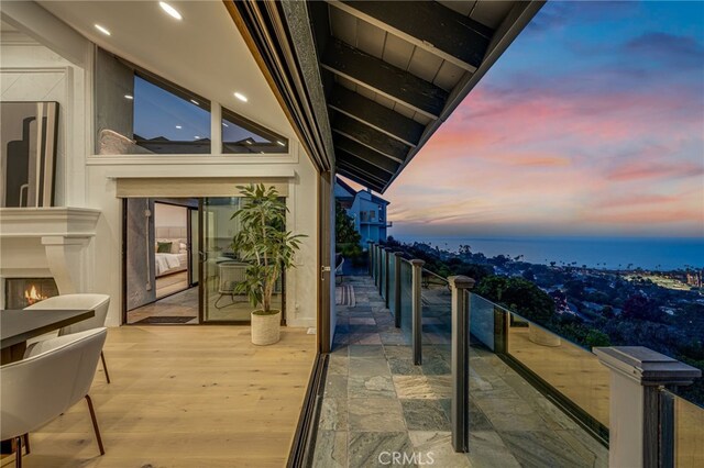 balcony at dusk featuring a water view