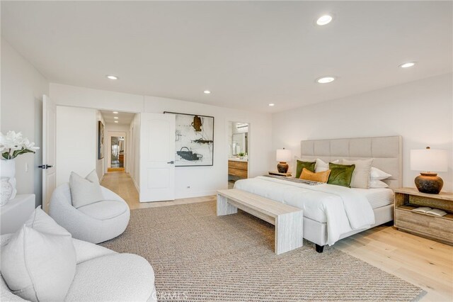 bedroom featuring ensuite bath and light hardwood / wood-style floors