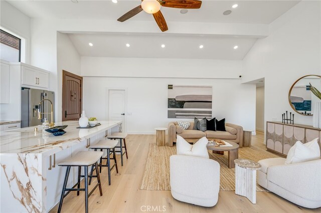 living room with beamed ceiling, ceiling fan, high vaulted ceiling, and light wood-type flooring