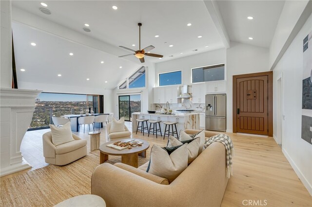 living room featuring ceiling fan, beam ceiling, high vaulted ceiling, and light wood-type flooring