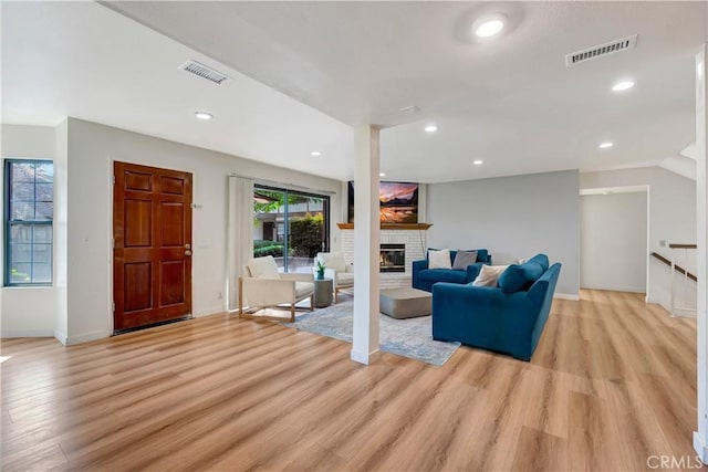 living room with a brick fireplace and light hardwood / wood-style flooring