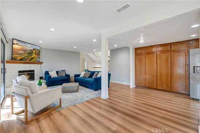 living room with a brick fireplace and light hardwood / wood-style flooring