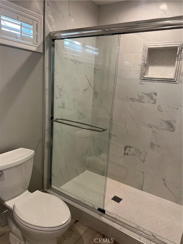 bathroom with an enclosed shower and toilet