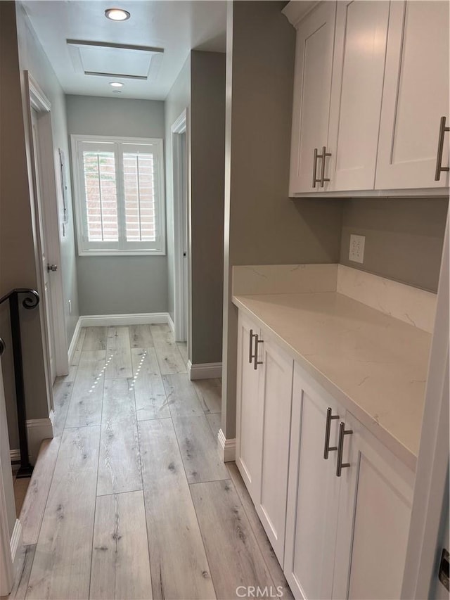 interior space featuring light hardwood / wood-style floors, white cabinets, and light stone countertops