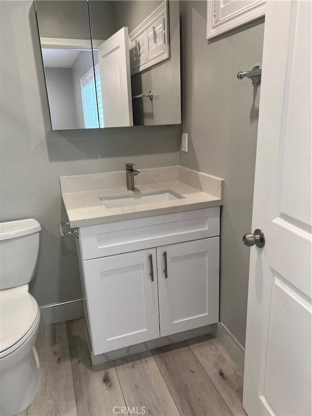 bathroom featuring hardwood / wood-style flooring, toilet, and vanity