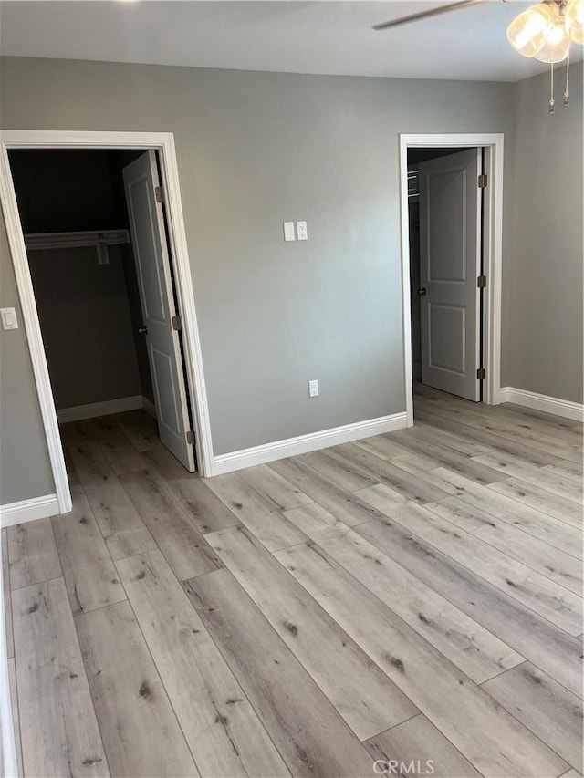 unfurnished bedroom featuring ceiling fan, light hardwood / wood-style floors, a spacious closet, and a closet