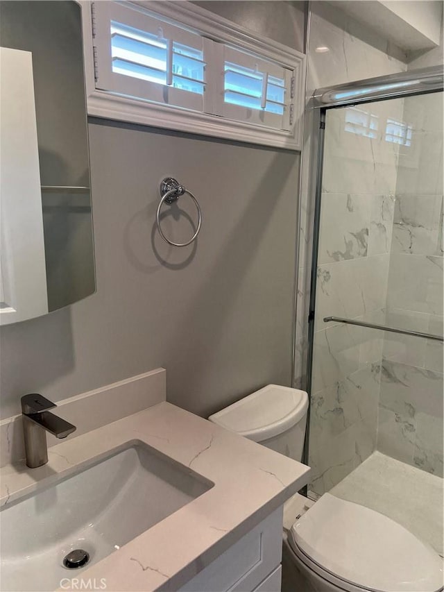 bathroom featuring an enclosed shower, vanity, and toilet