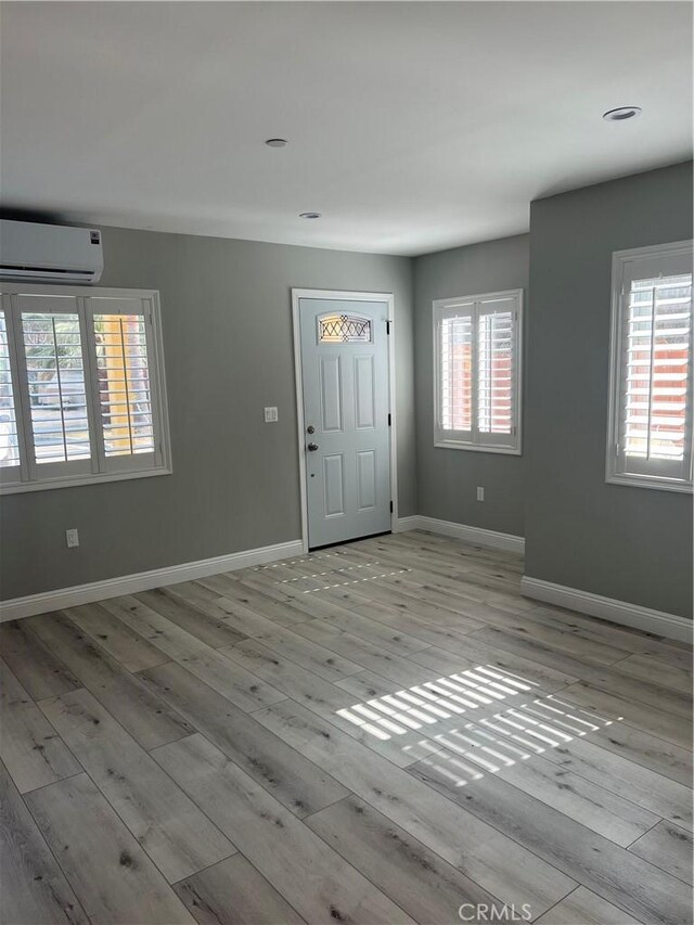 entrance foyer featuring an AC wall unit and light wood-type flooring