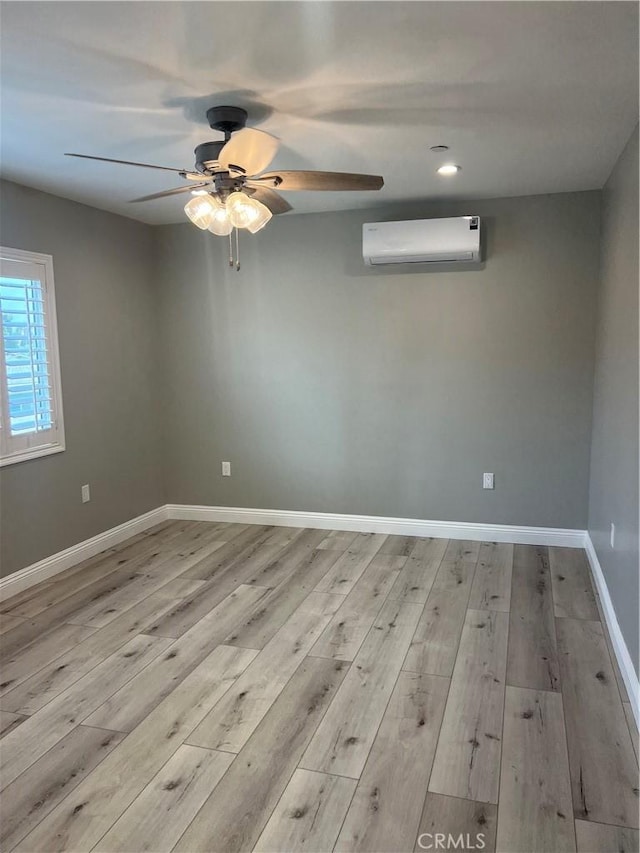 unfurnished room with a wall mounted AC and light hardwood / wood-style floors