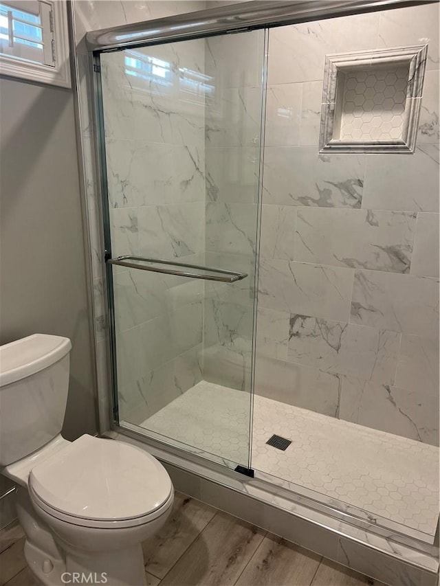 bathroom featuring a shower with shower door and toilet