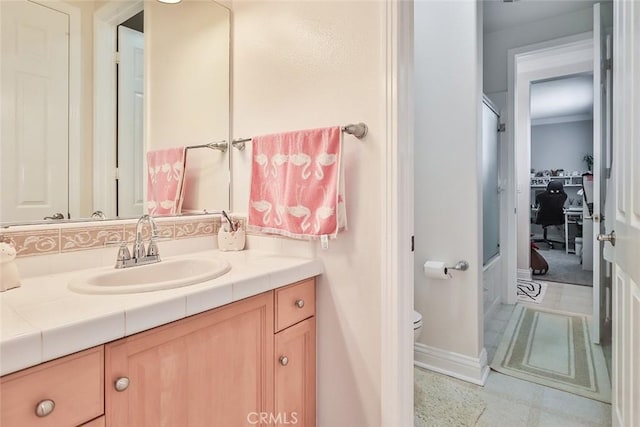 bathroom featuring toilet, ornamental molding, and vanity