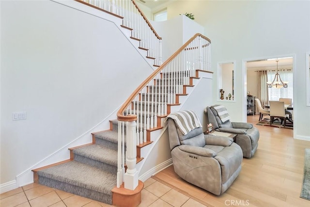 staircase with an inviting chandelier, hardwood / wood-style floors, and a high ceiling