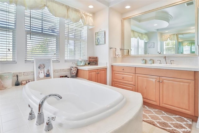 bathroom with vanity, plenty of natural light, and a relaxing tiled tub