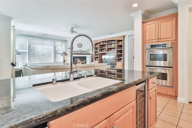 kitchen featuring ceiling fan, ornamental molding, double oven, and sink