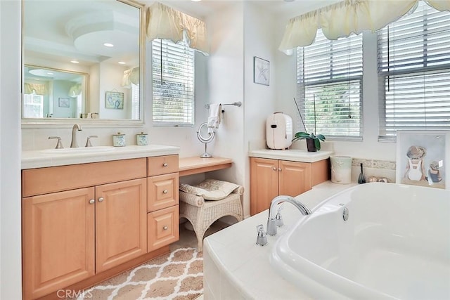 bathroom with a healthy amount of sunlight, vanity, and tiled tub