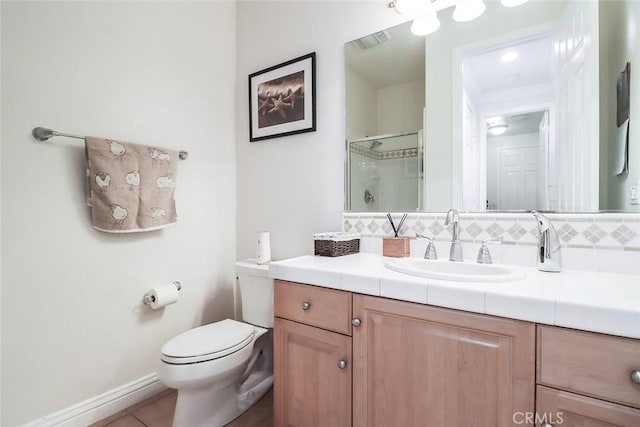 bathroom with toilet, vanity, tasteful backsplash, tile patterned floors, and a shower with door