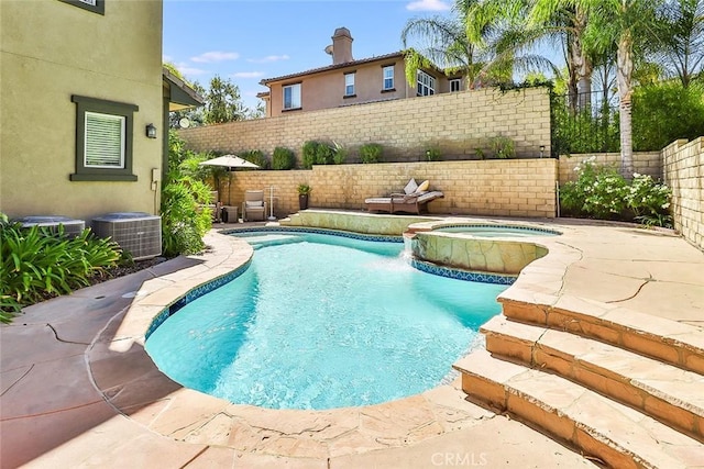 view of swimming pool with pool water feature, a patio area, central AC, and an in ground hot tub