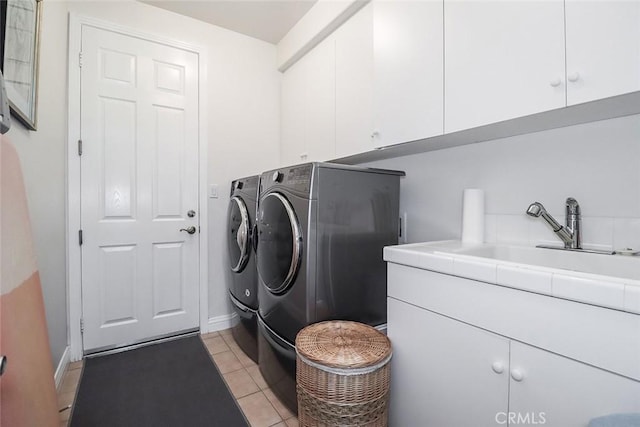 clothes washing area with light tile patterned floors, cabinets, and washer and dryer