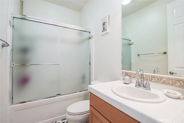 full bathroom featuring toilet, enclosed tub / shower combo, and vanity