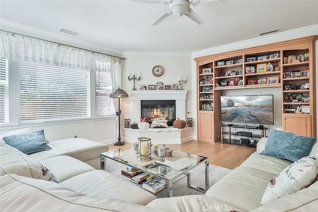 living room featuring light hardwood / wood-style floors, ornamental molding, and ceiling fan