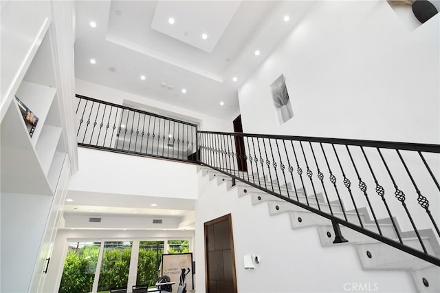 stairs featuring a tray ceiling and a high ceiling