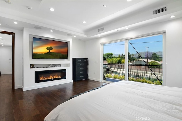 bedroom with multiple windows, dark hardwood / wood-style flooring, and access to outside