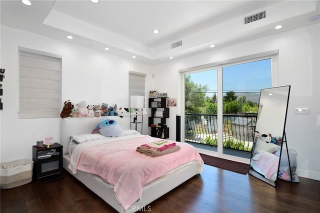 bedroom featuring access to exterior, dark hardwood / wood-style flooring, and a raised ceiling