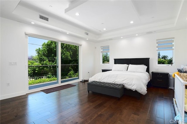 bedroom with dark hardwood / wood-style floors and a tray ceiling