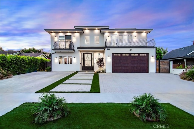 view of front of home with a balcony, a yard, and a garage