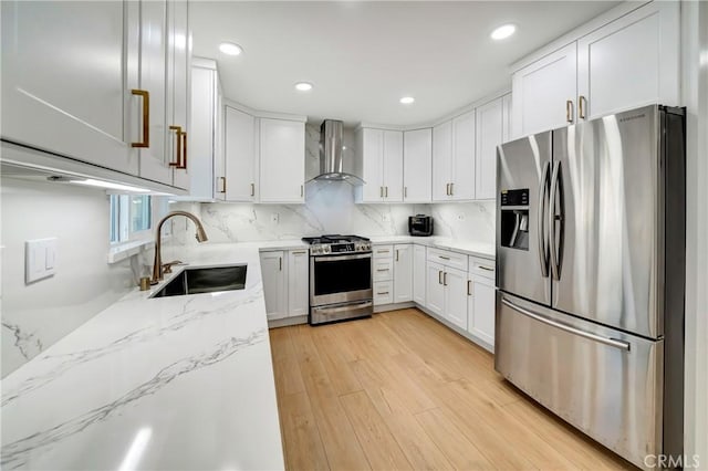 kitchen with backsplash, wall chimney range hood, sink, stainless steel appliances, and white cabinets