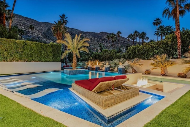 view of pool featuring a mountain view, pool water feature, and an outdoor fire pit